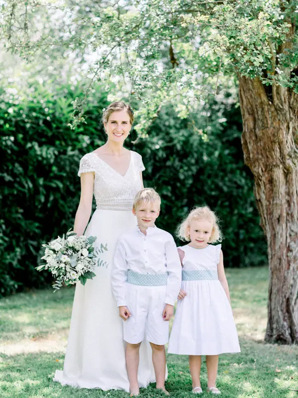 Mariée et deux enfants d'honneur en blanc sous un arbre, mariage en Normandie