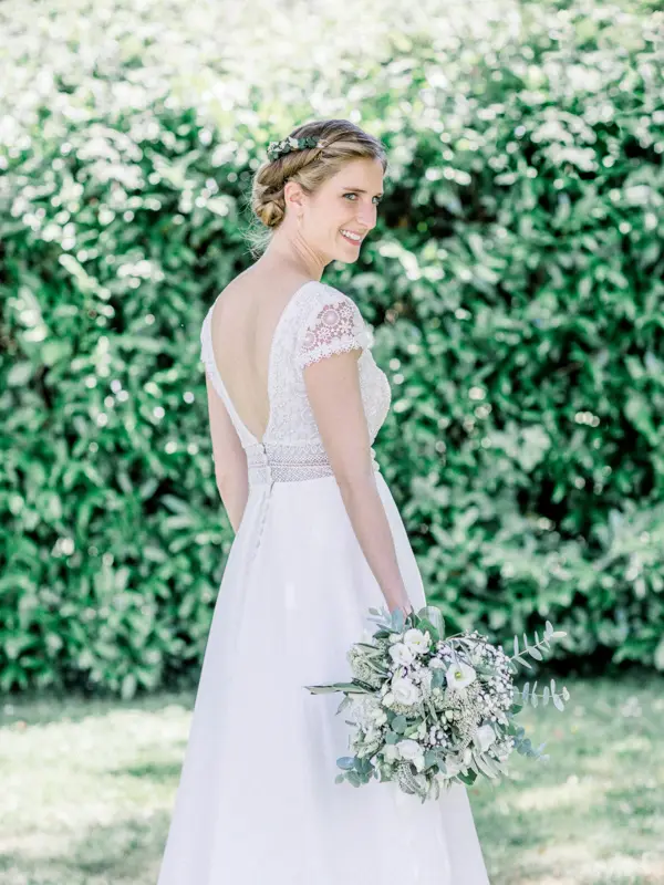 Mariée de dos en robe au dos nu devant une haie, à Écrosville