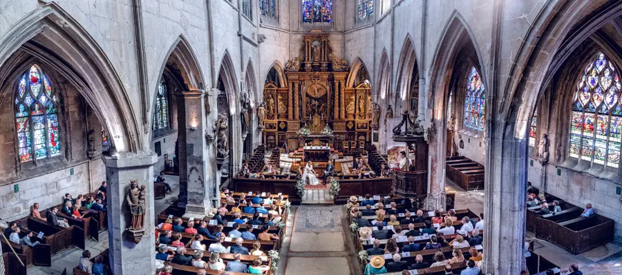 Nef gothique de l'église de Pont-de-l'Arche remplie d'invités pendant la messe