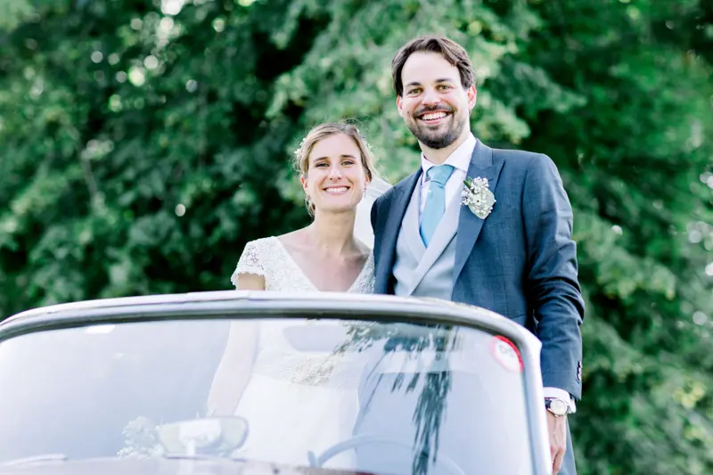 Mariés souriants debout dans la voiture ancienne décapotable