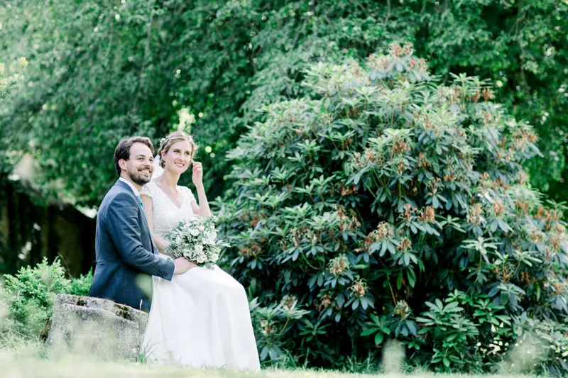 Mariés assis près d'un grand massif de rhododendrons dans le parc d'Argeronne