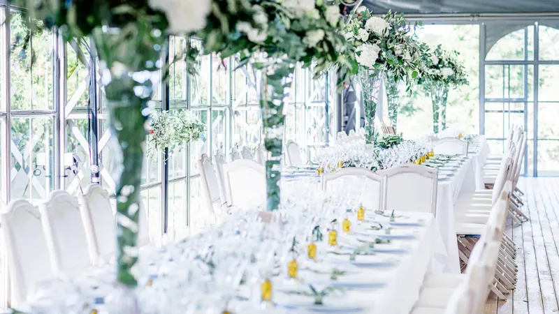 Tables blanches sous les guirlandes de verdure de l'orangerie