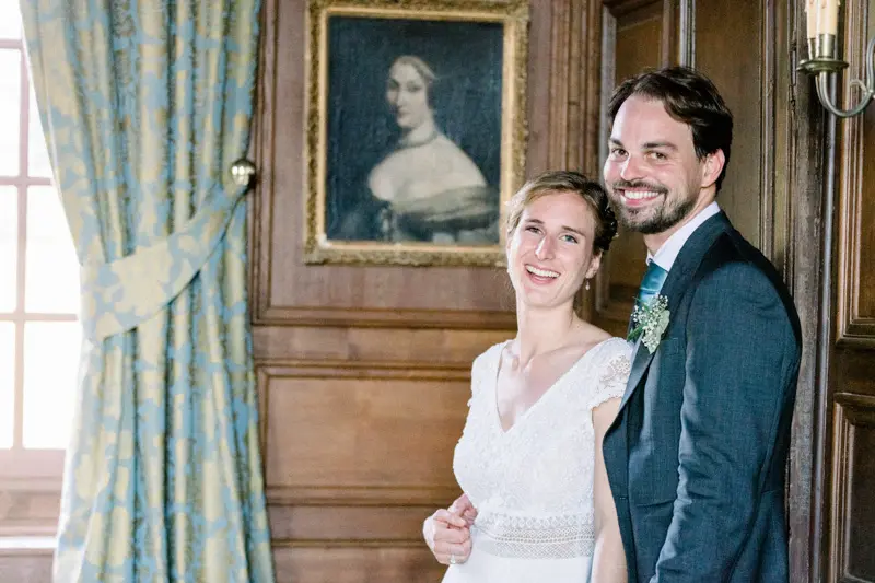 Mariés souriants dans un salon boisé sous un portrait ancien