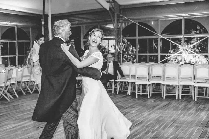 La mariée danse avec un invité sur le parquet de l'orangerie, en noir et blanc