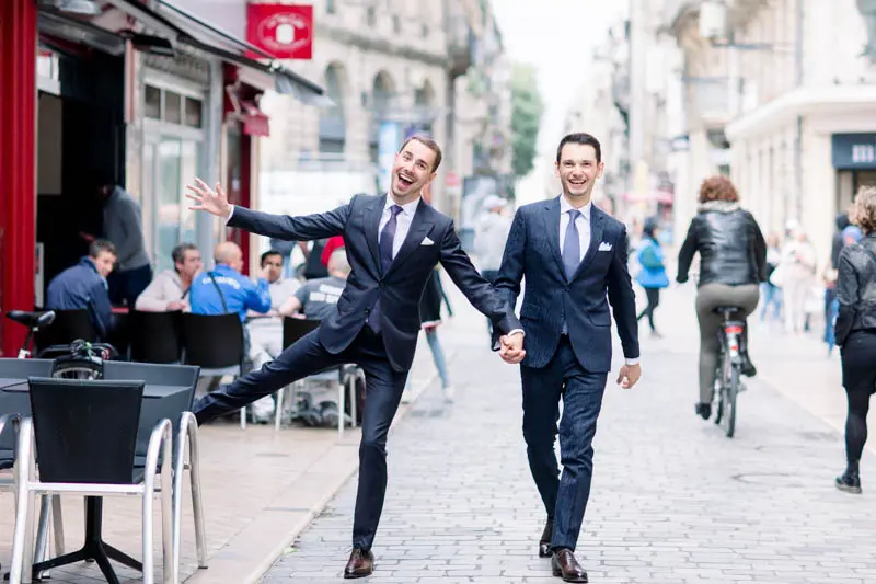 The two grooms in blue suits dancing down a pedestrian street in Bordeaux