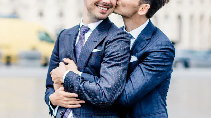 The grooms cheek to cheek in blue suits in the streets of Bordeaux