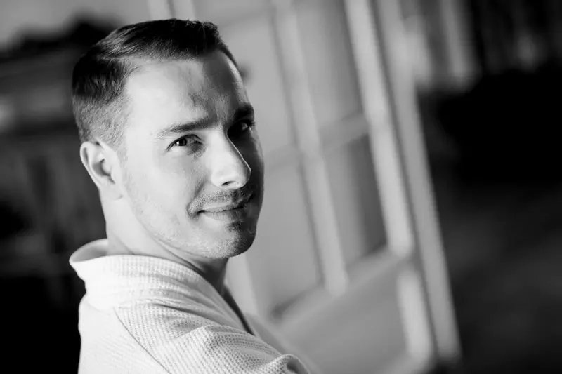 Portrait of a smiling groom in a bathrobe while getting ready, in black and white