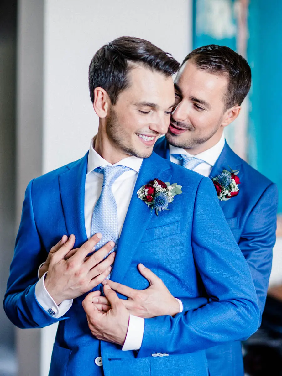 David and Pierre embracing and smiling at their first look, portrait format
