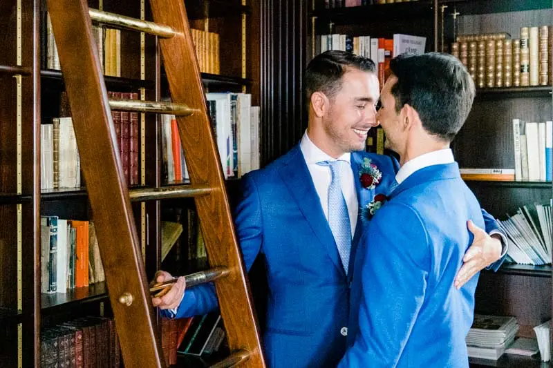 The two grooms kissing in the wood-panelled library of Villa La Tosca