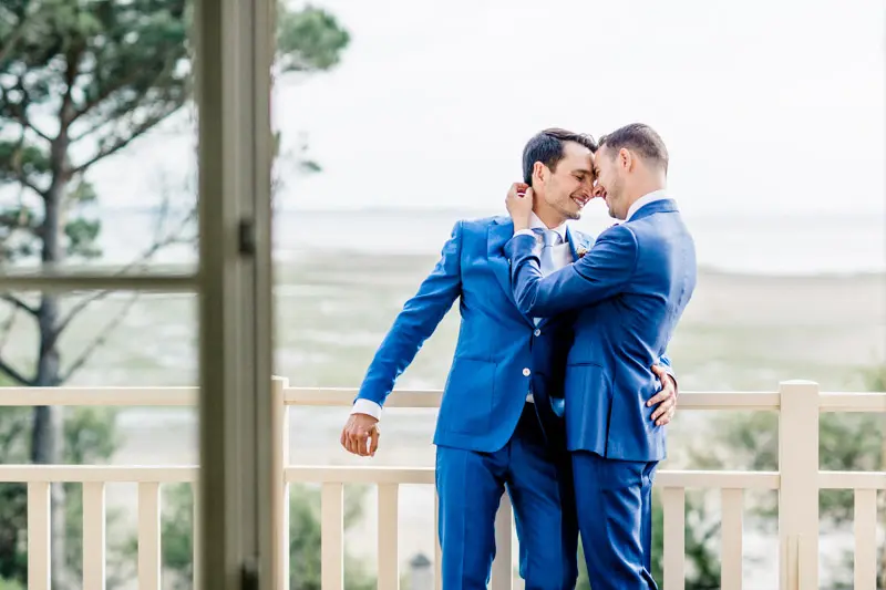The grooms embracing on the terrace overlooking Arcachon Bay