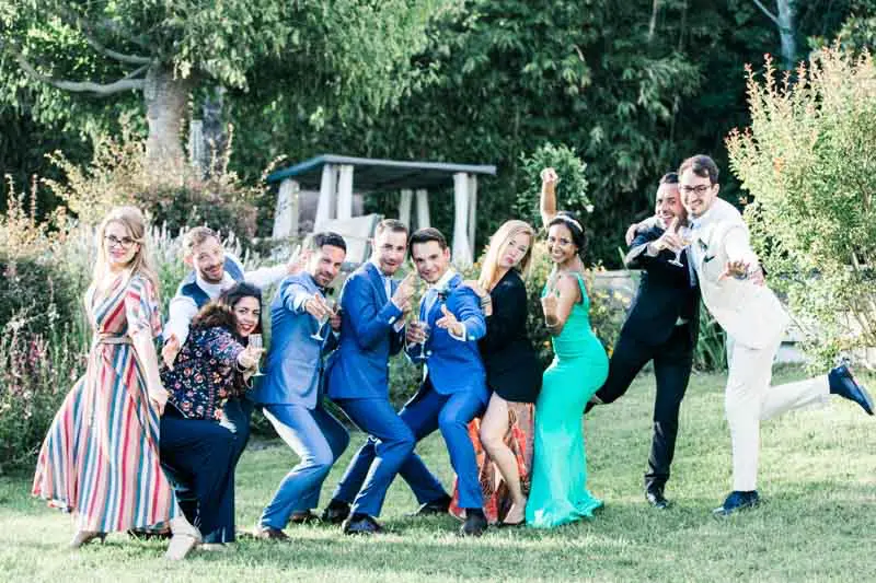 Playful group photo of the grooms and their friends on the villa lawn