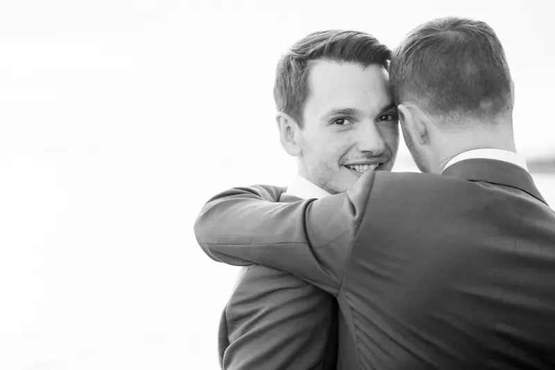 The two grooms sharing a tender moment by Arcachon Bay, in black and white