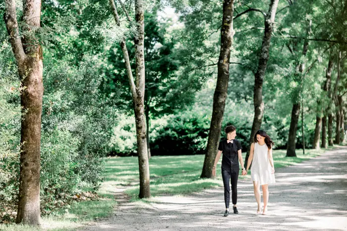 The couple walking hand in hand along a shady path in the Parc Bordelais