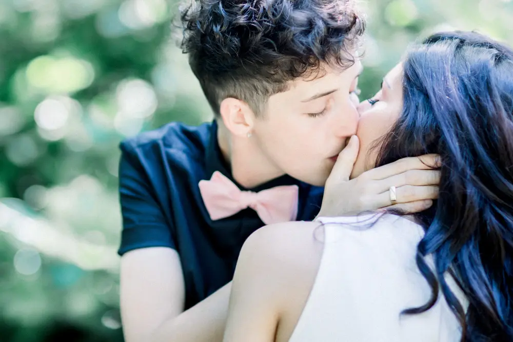 Close-up kiss, pink bow tie and a hand in the hair