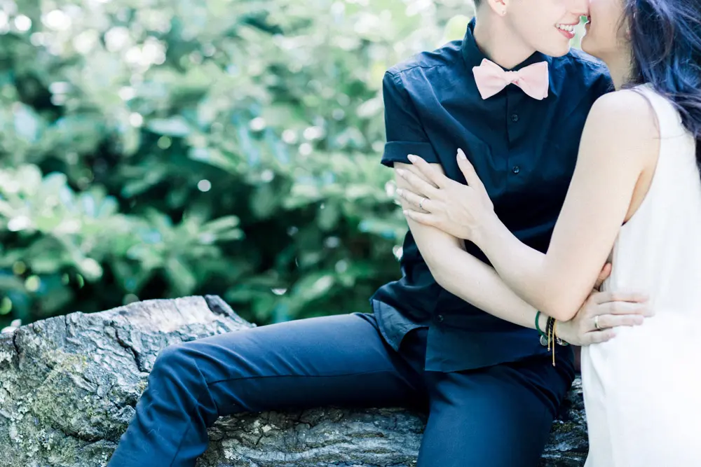 The couple sitting entwined on a fallen tree trunk in the park