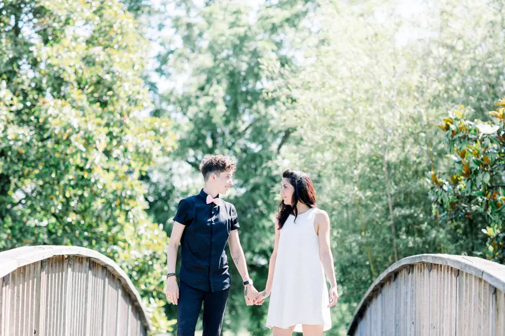 The couple hand in hand on a small wooden bridge in the Parc Bordelais
