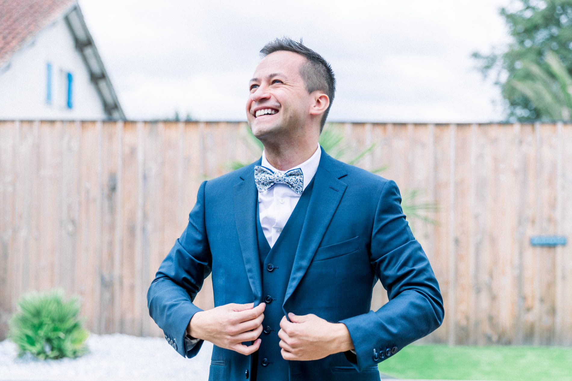 Smiling groom adjusting his blue suit jacket while getting ready