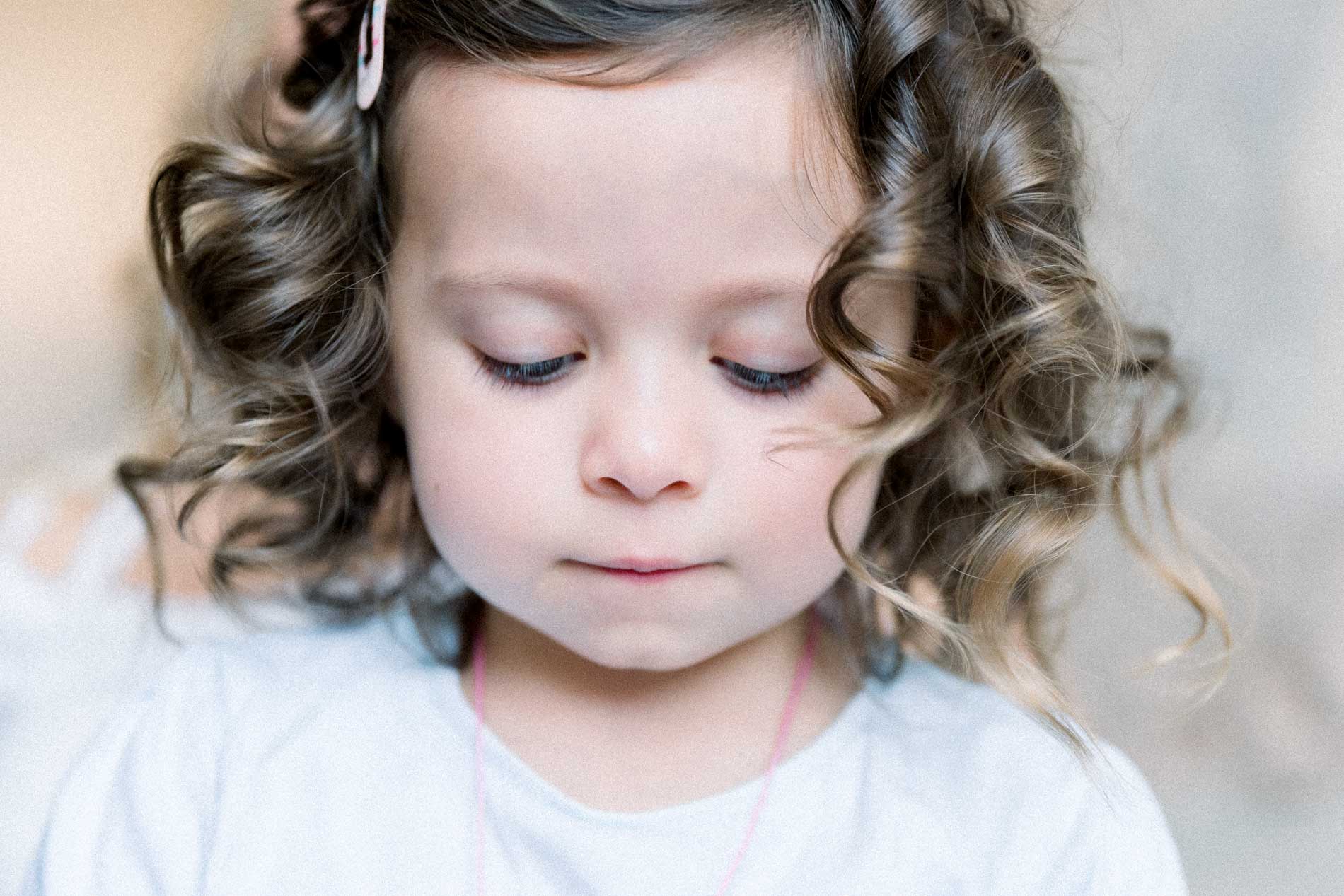 Little girl with curly hair looking down on the wedding day