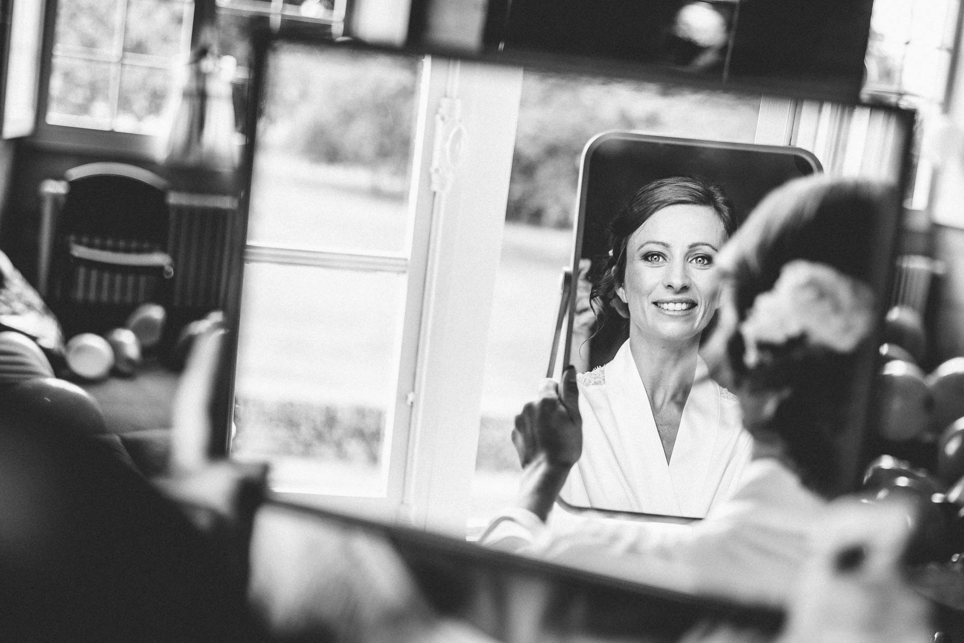 The bride's reflection in a mirror as she gets ready, in black and white