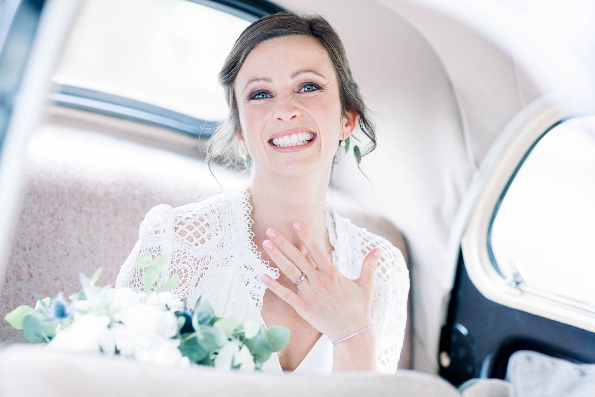 Bride overcome with emotion in the vintage car, hand on her chest