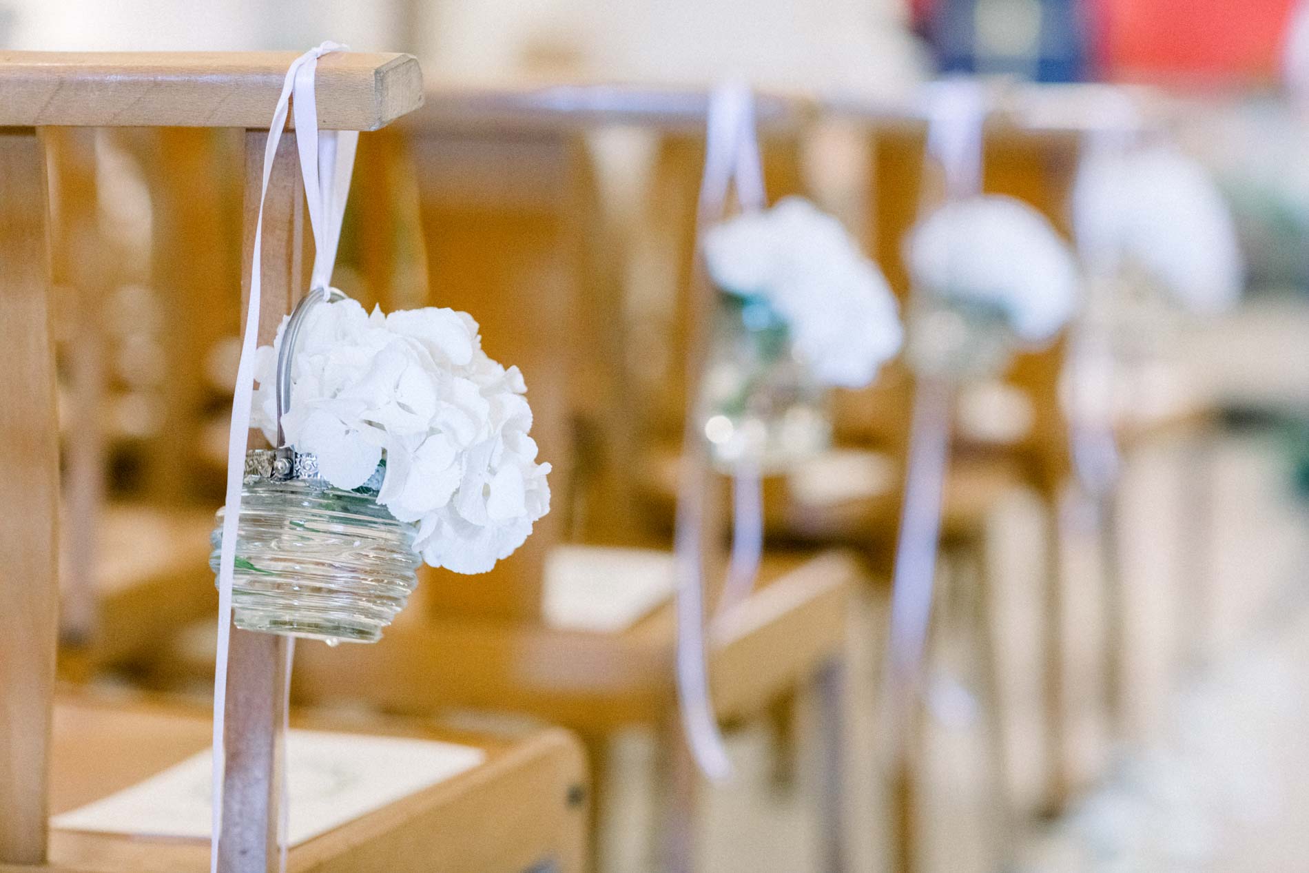 Baskets of white hydrangeas hanging from the church pews