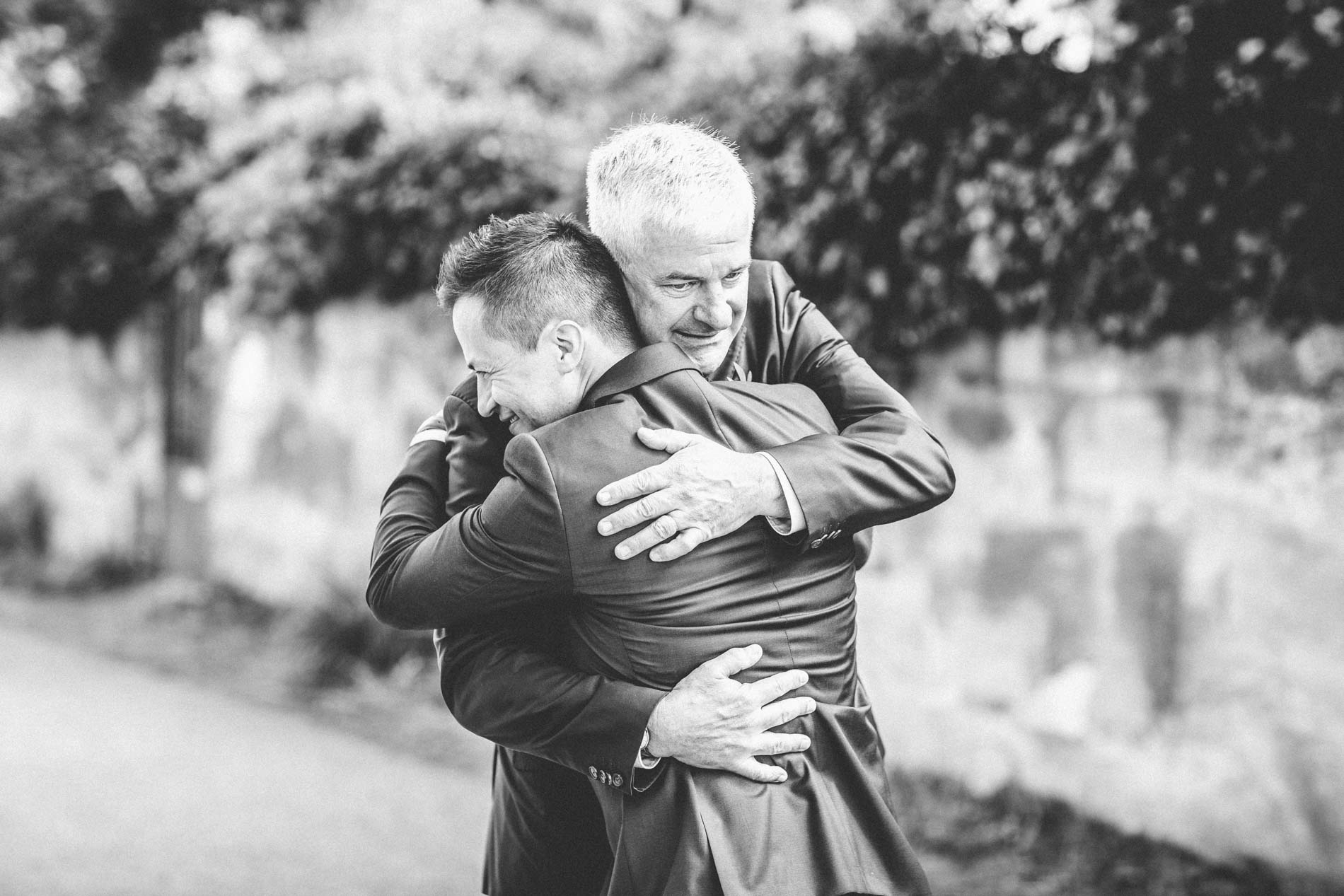 A warm embrace between the groom and a guest at the church, in black and white