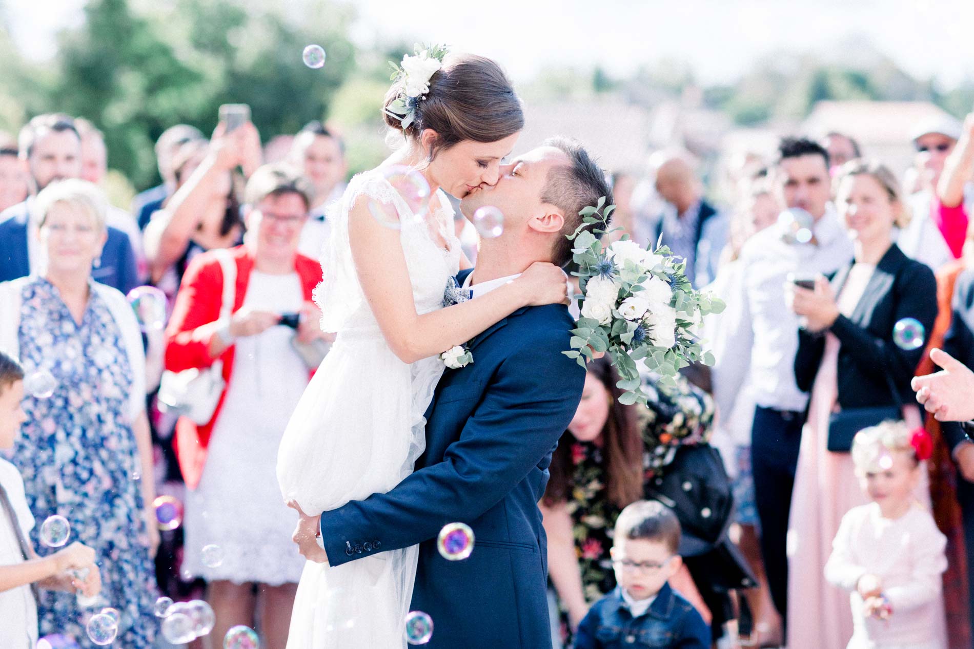 The couple kissing under soap bubbles outside the Eysines church
