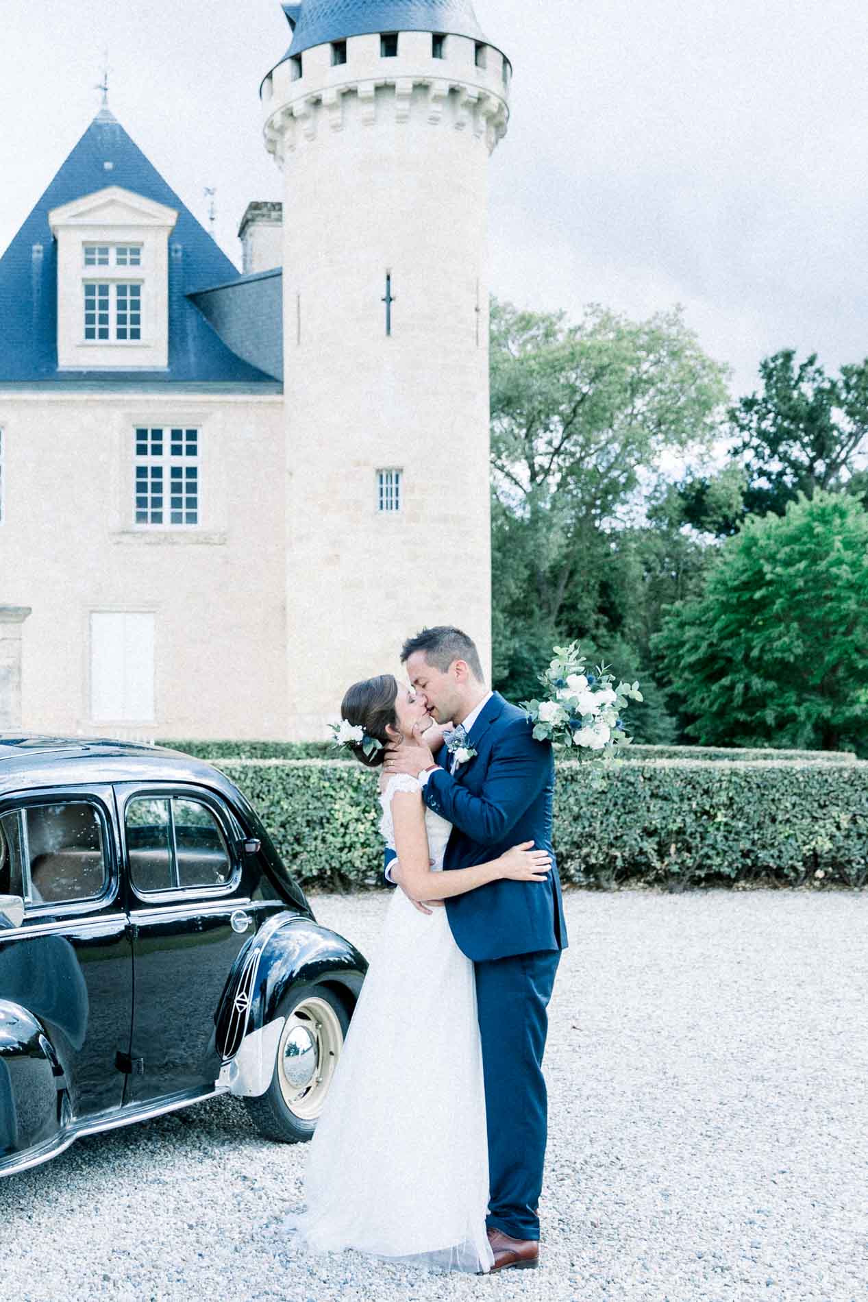 The couple kissing by the vintage car at the foot of the château tower