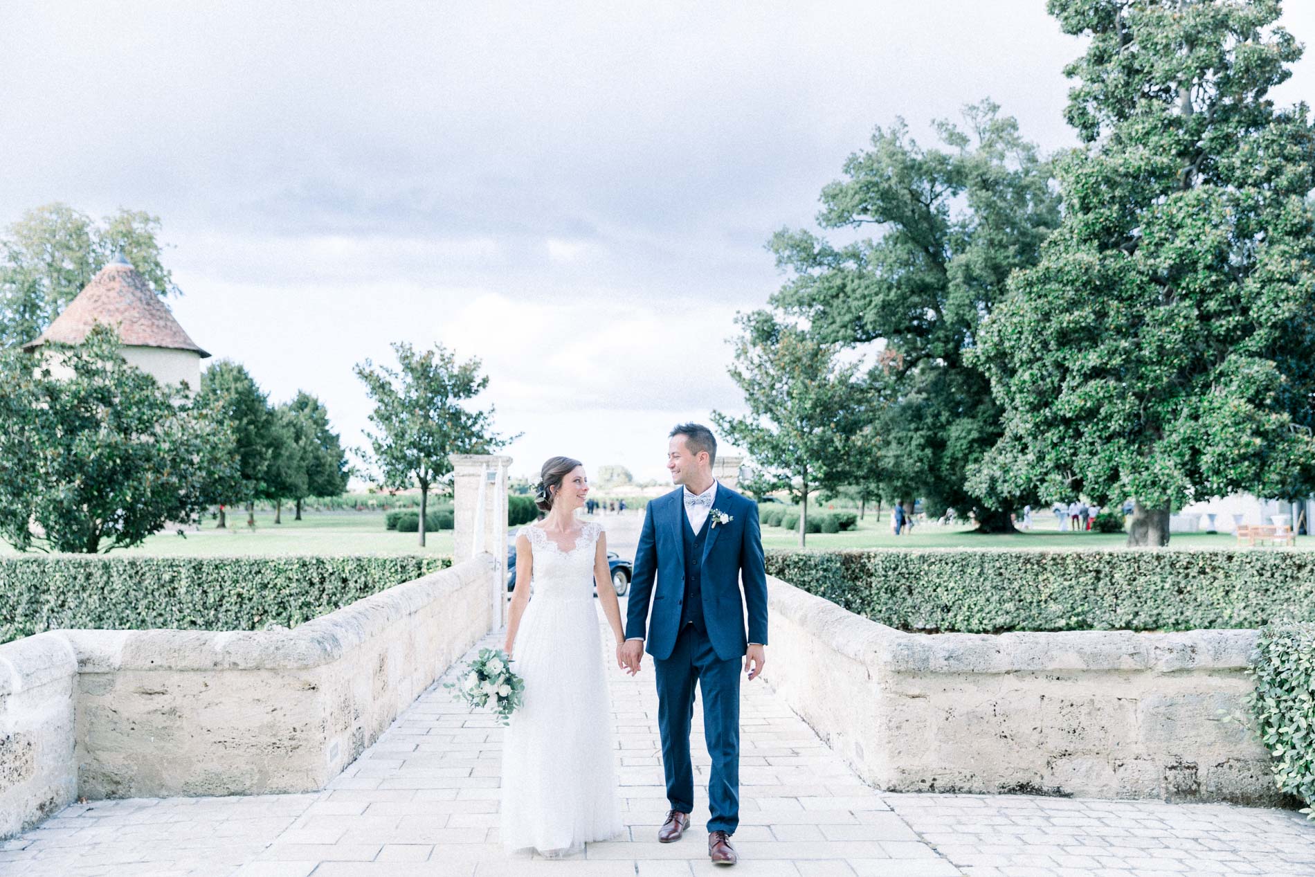 Bride and groom walking hand in hand on the bridge to Château d'Agassac in the Haut-Médoc