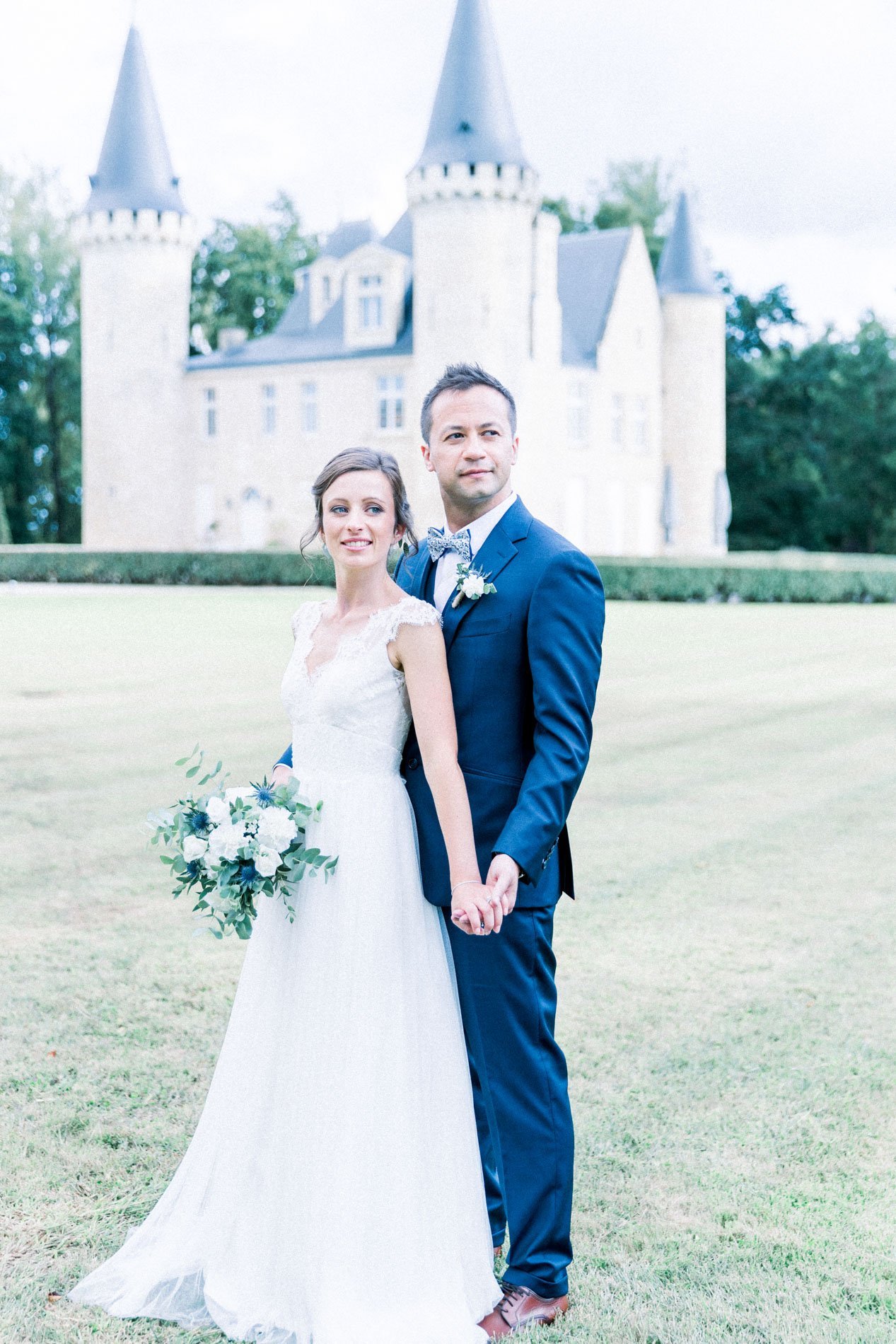 The bride and groom side by side on the lawn before the château