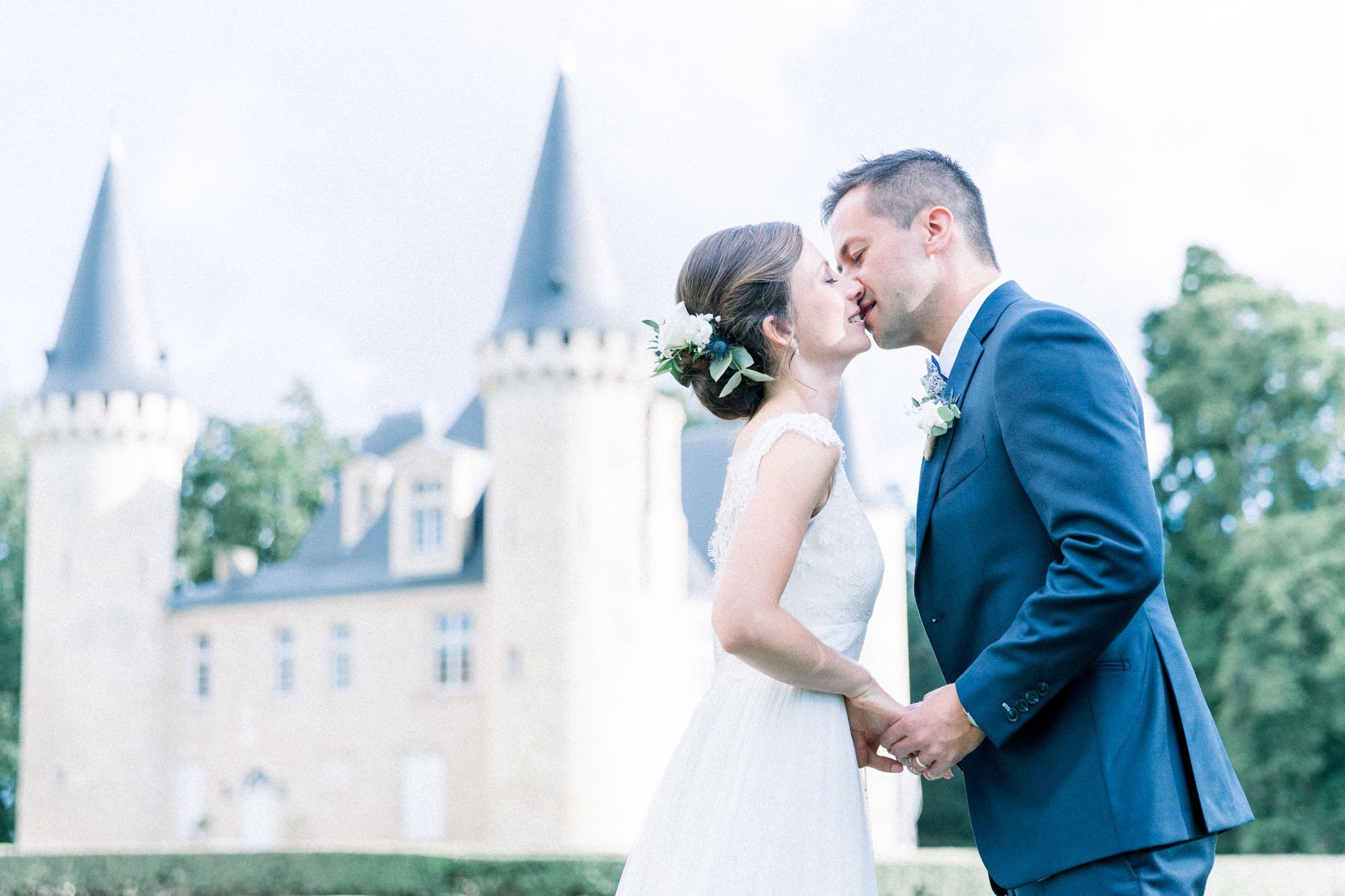 The couple kissing hand in hand in the château grounds