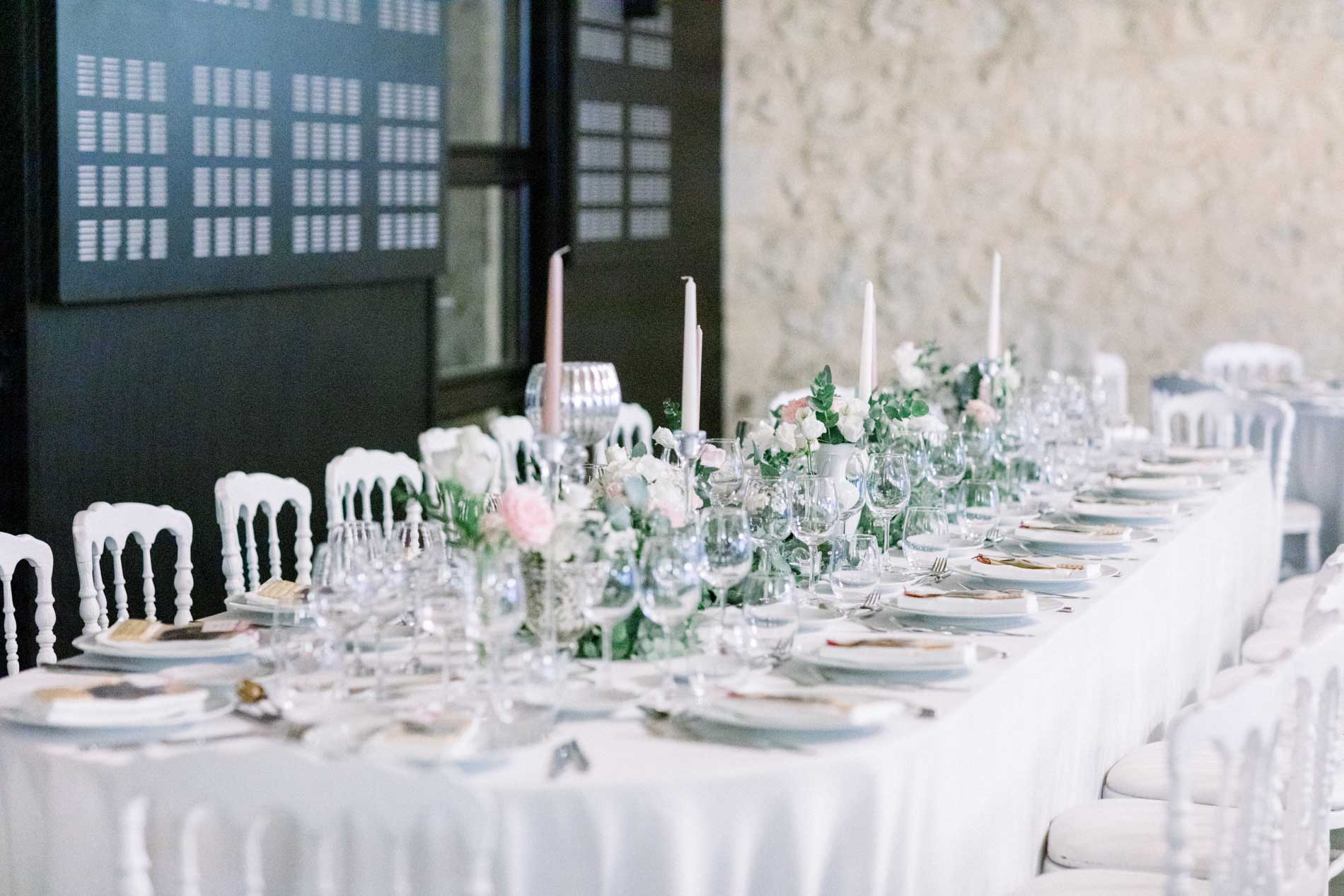 Long head table laid with flowers and white chairs