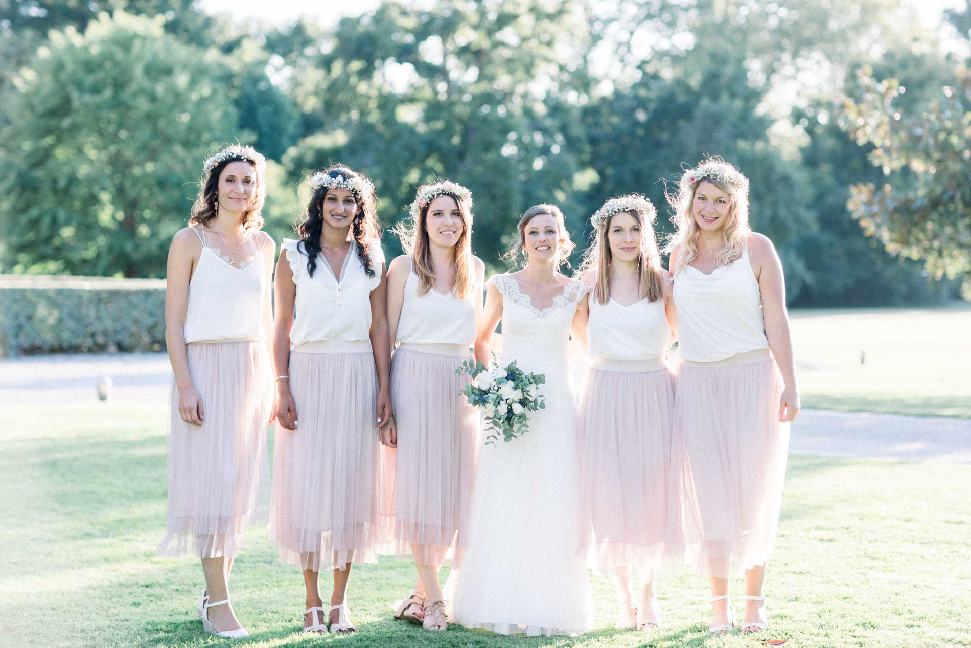 The bride with her bridesmaids in pink skirts and flower crowns