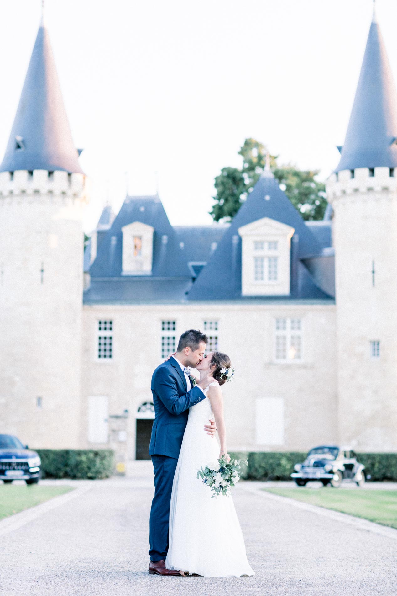 The couple kissing in front of the façade and towers of Château d'Agassac