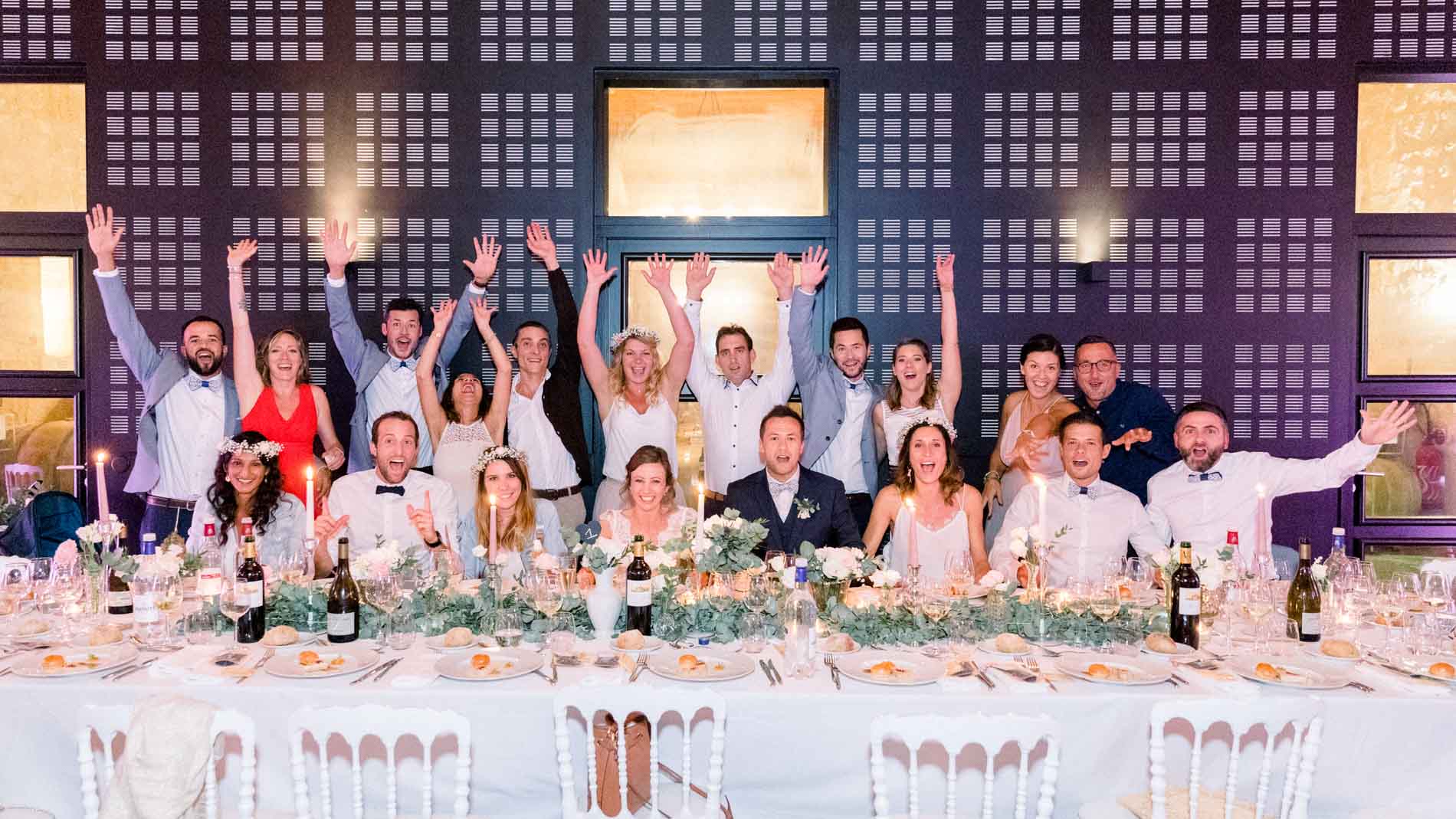 Guests raising their arms around the long table during the evening party