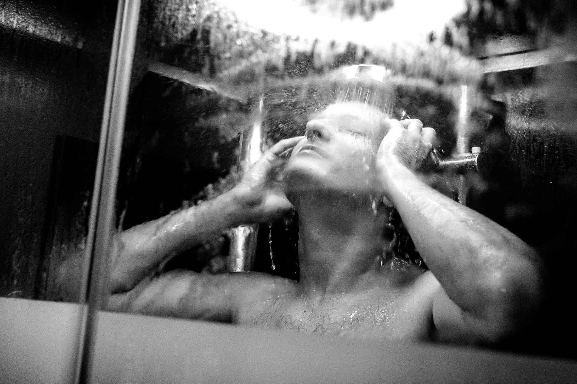 The groom splashing his face in the shower, in black and white
