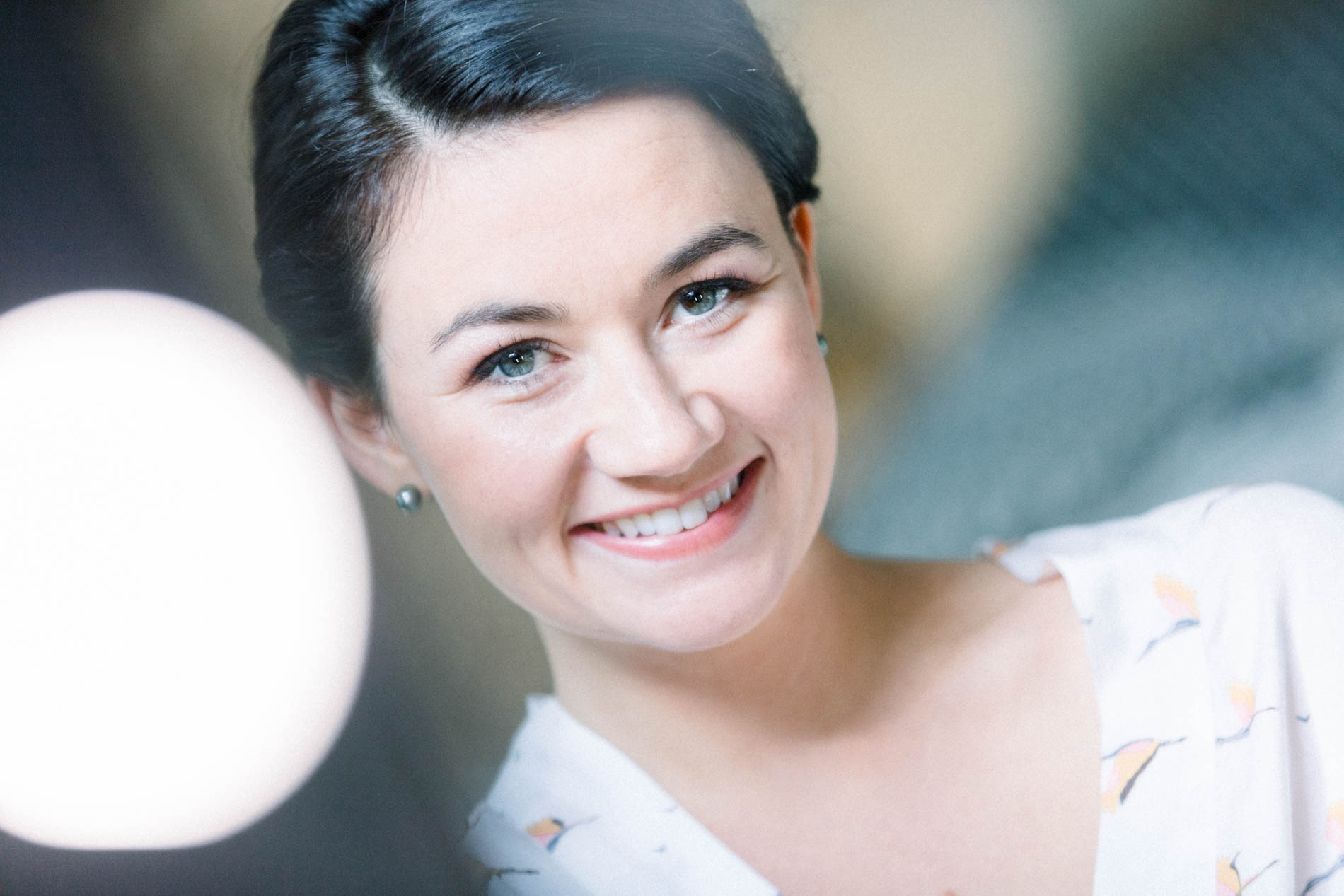 The bride with her hair in a chignon, beaming while getting ready