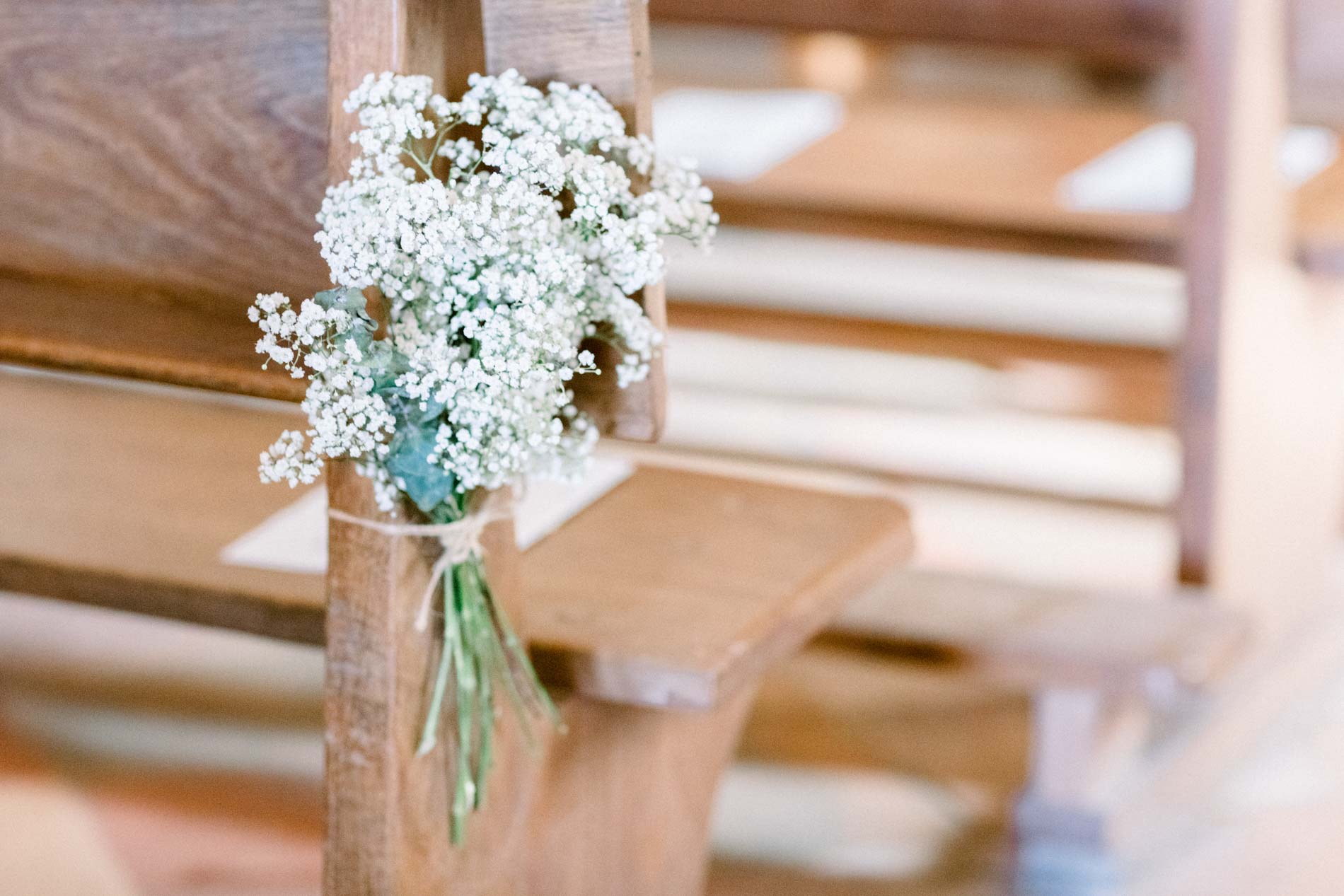 A gypsophila posy tied to the end of a church pew