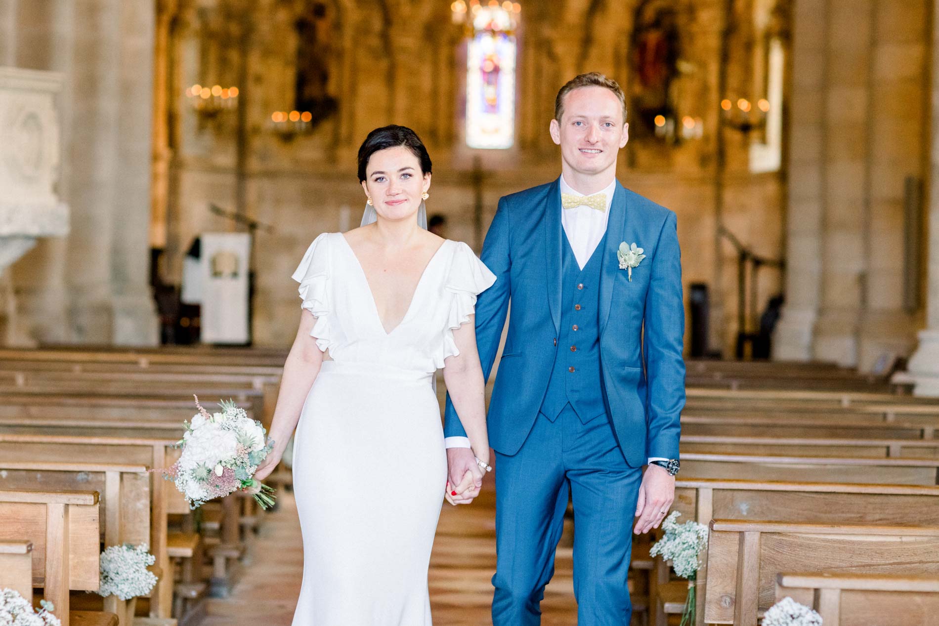 The bride and groom hand in hand in the aisle of Montagne church