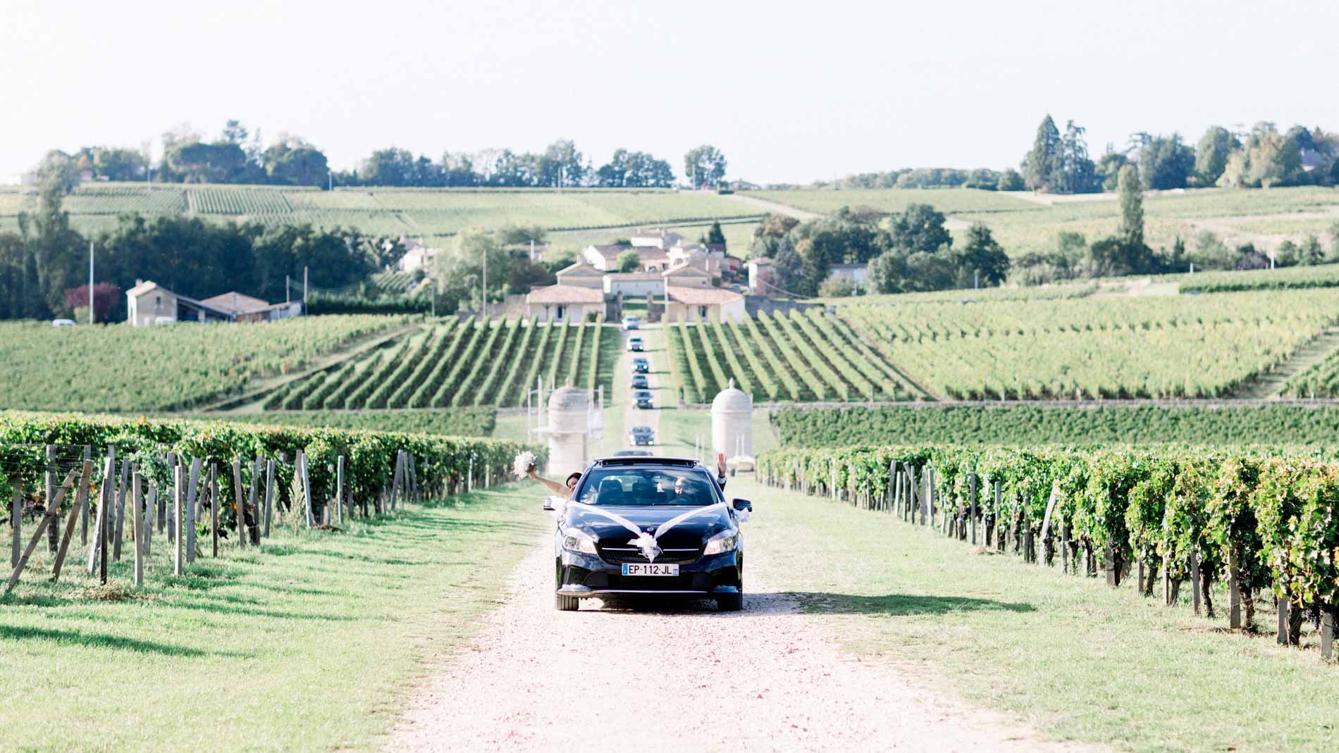 The wedding car driving up the lane between the Saint-Émilion vines