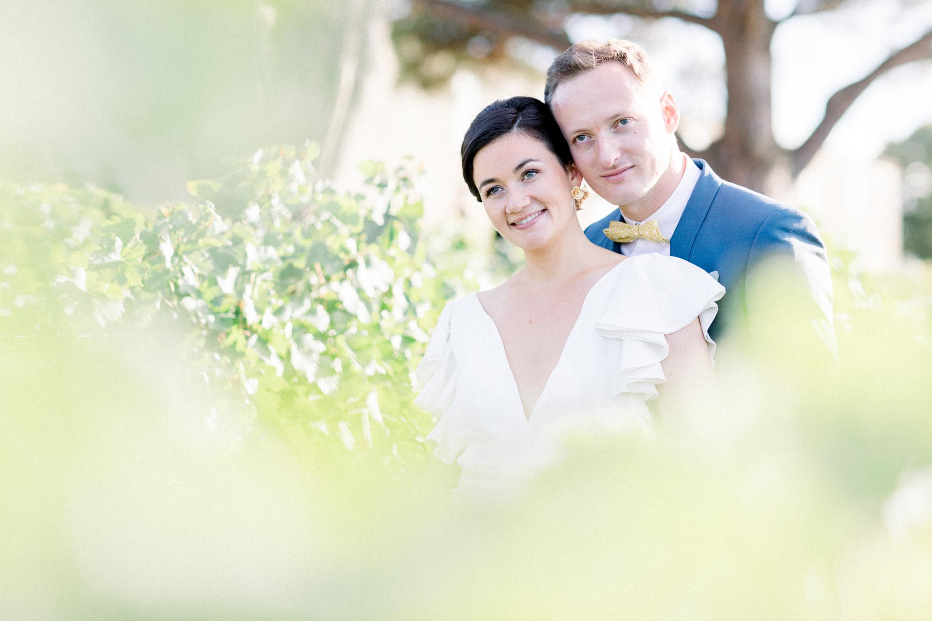 The smiling couple seen through vine leaves in the foreground