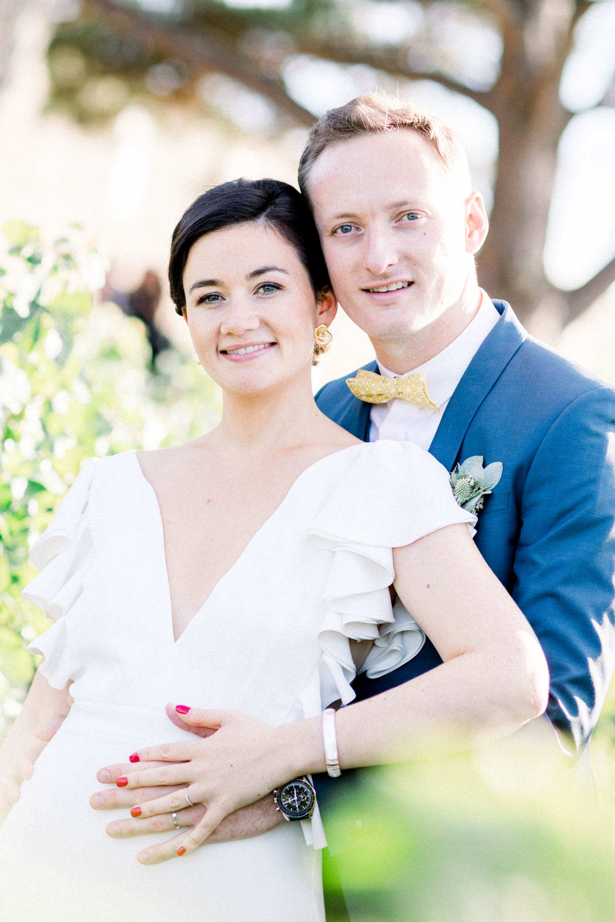 The groom hugging the bride from behind in the vines
