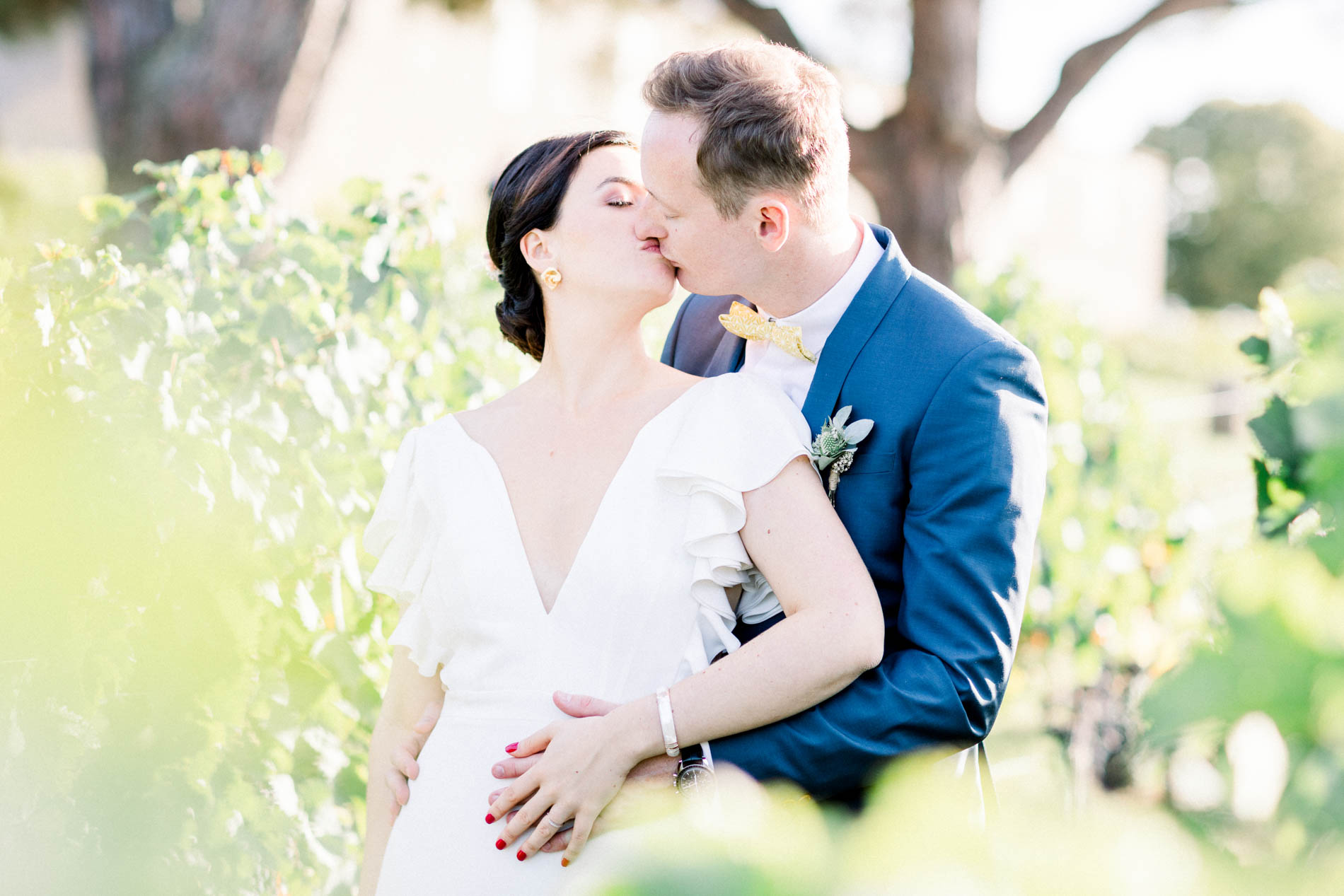 The bride and groom kissing in the vines of Château Saint-Georges