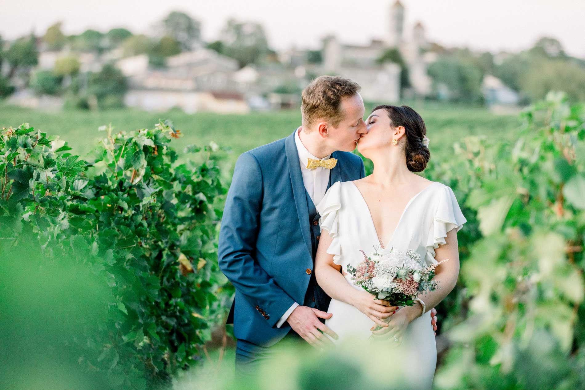The couple in the vines with a village bell tower behind them