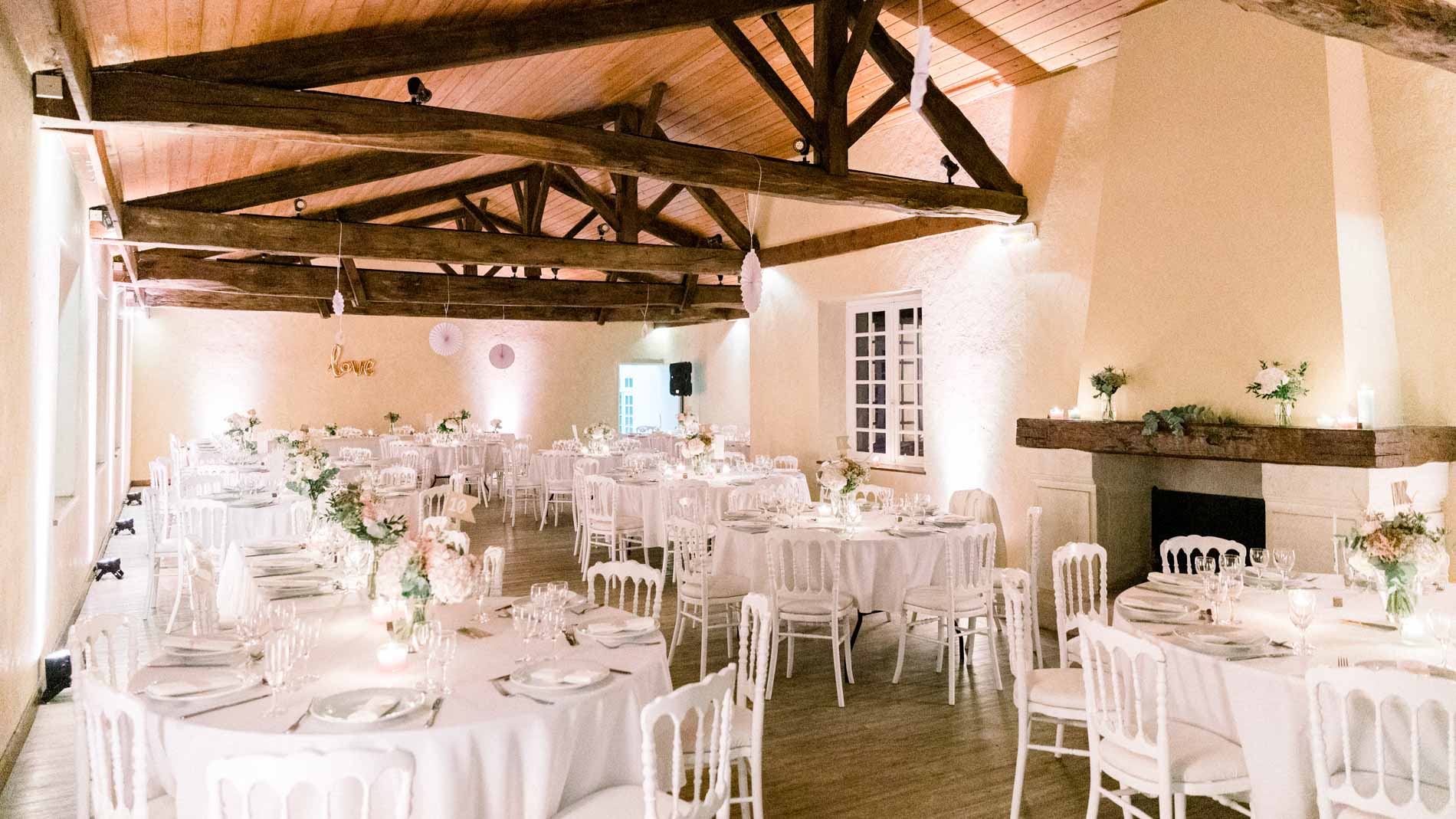 Dining hall under exposed beams with round white-clothed tables