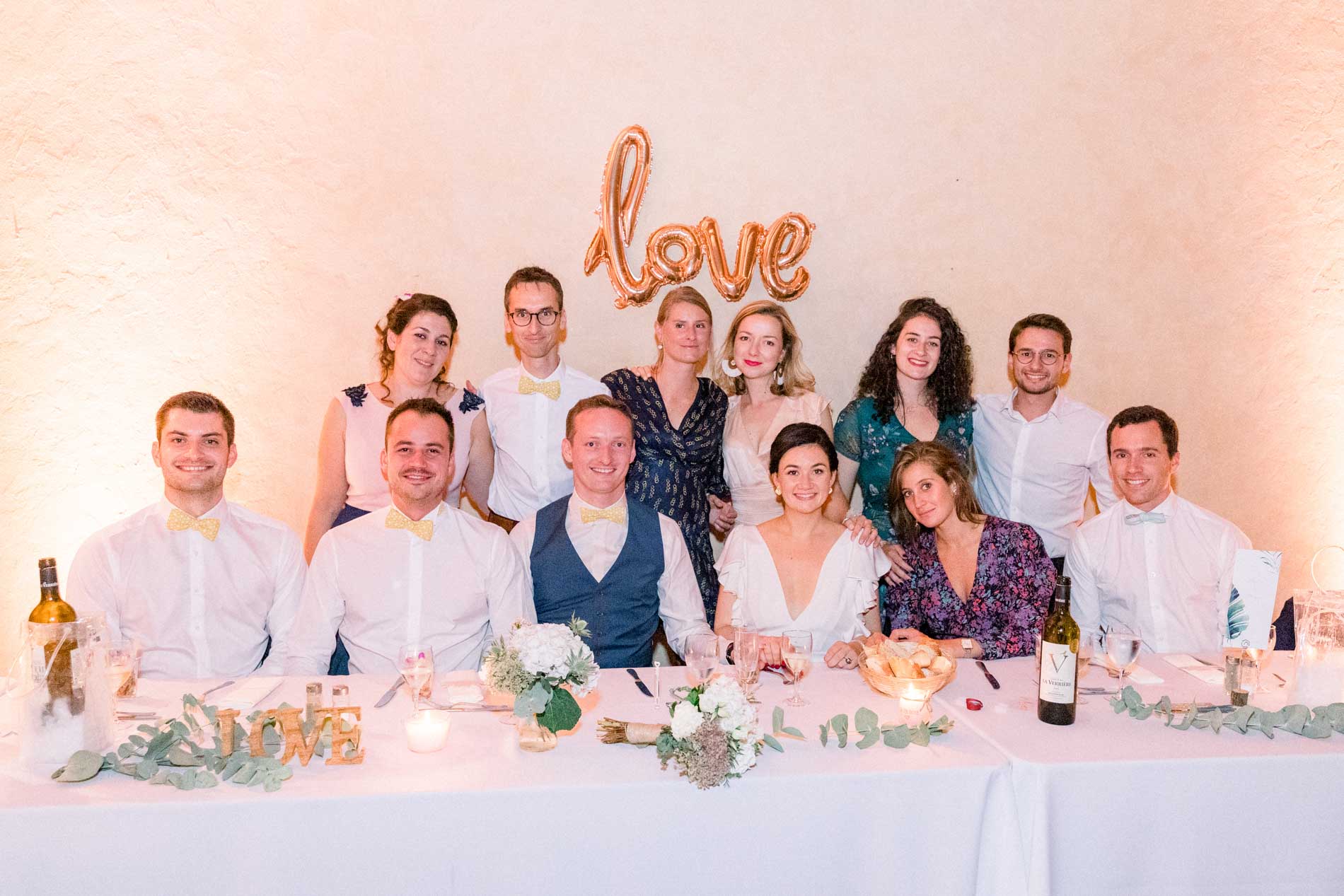 The couple and their friends at the top table beneath the "love" balloon