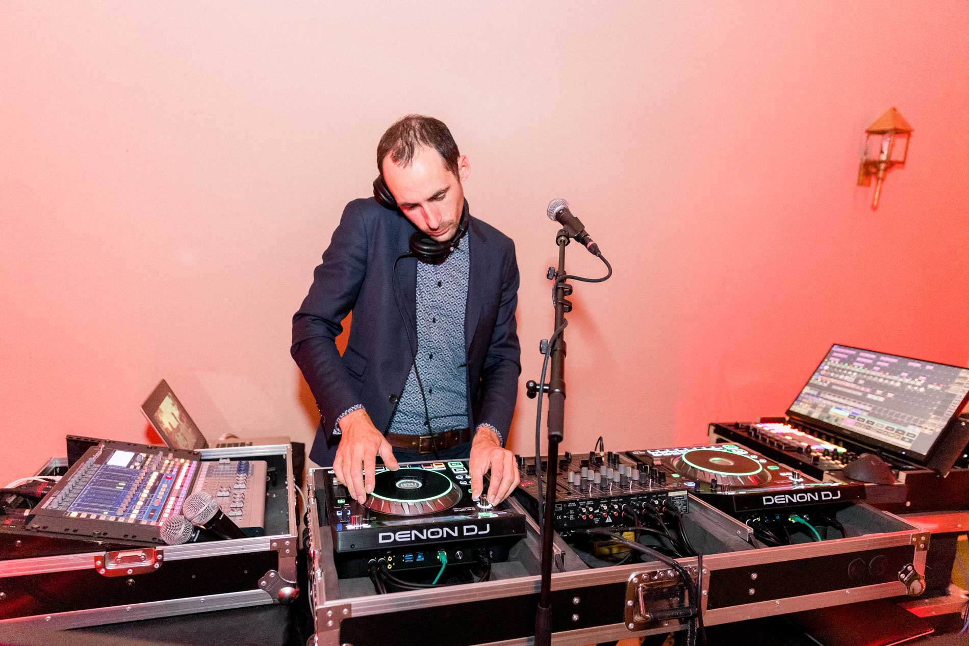 The DJ at the decks under red lighting during the wedding party