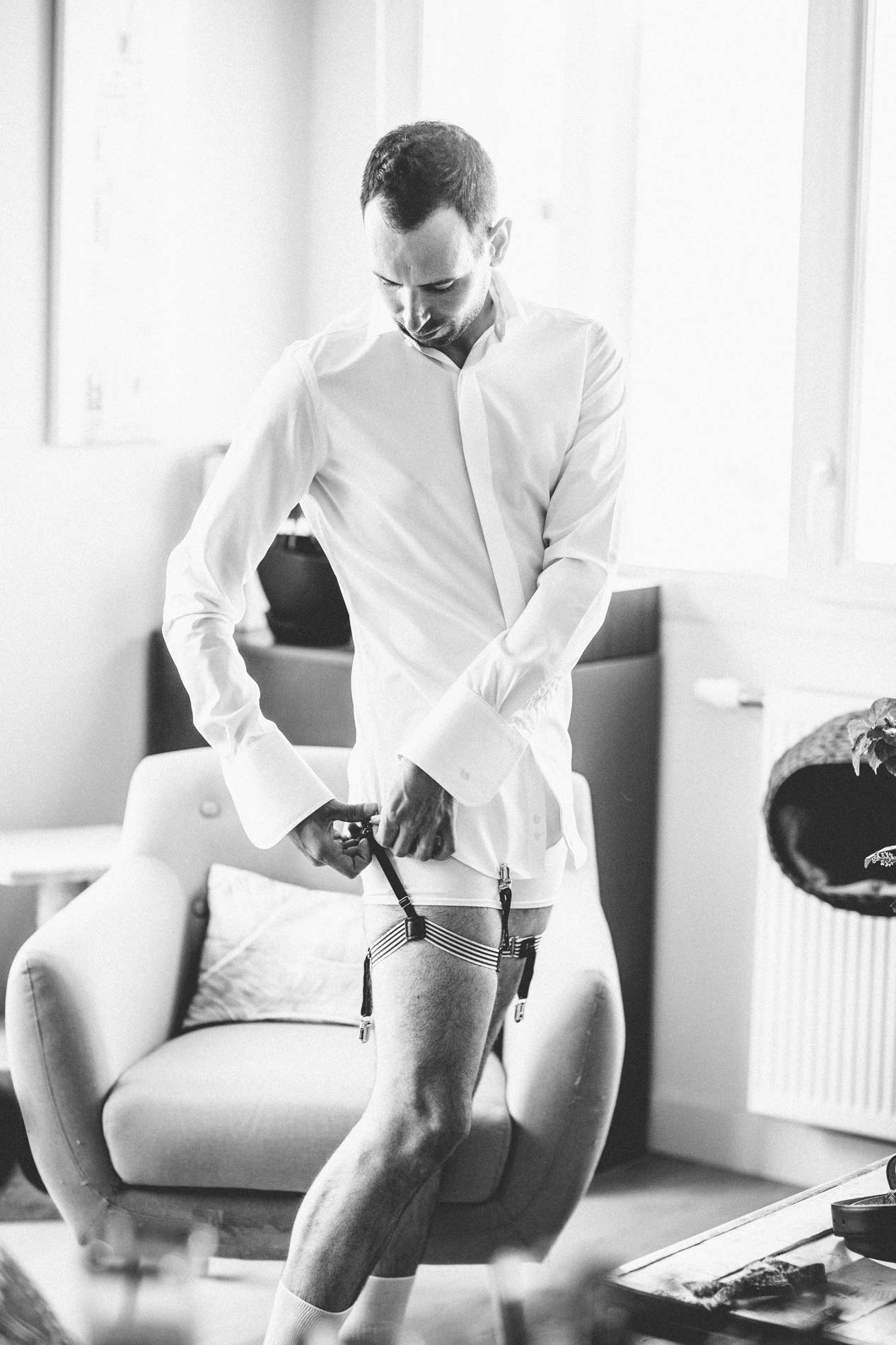 Marié enfilant son pantalon pendant les préparatifs, en noir et blanc