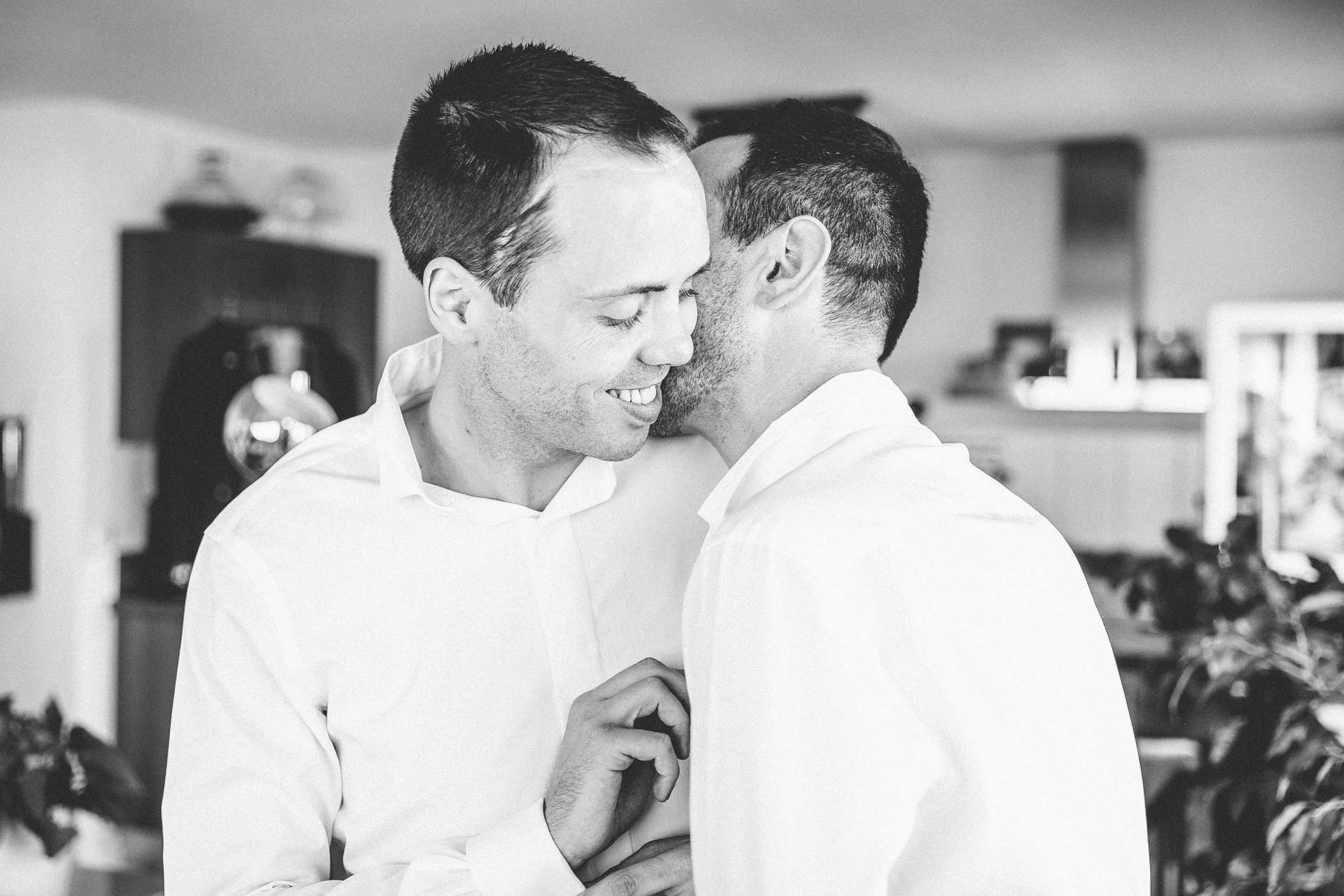 Les deux mariés complices pendant l'habillage, en noir et blanc