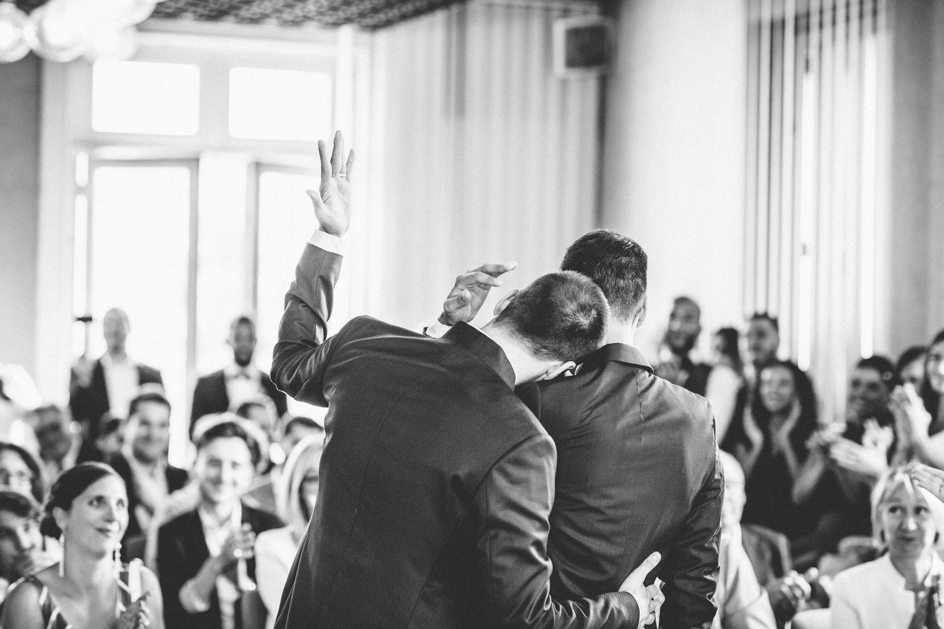 Mariés enlacés et invités applaudissant à la mairie, en noir et blanc